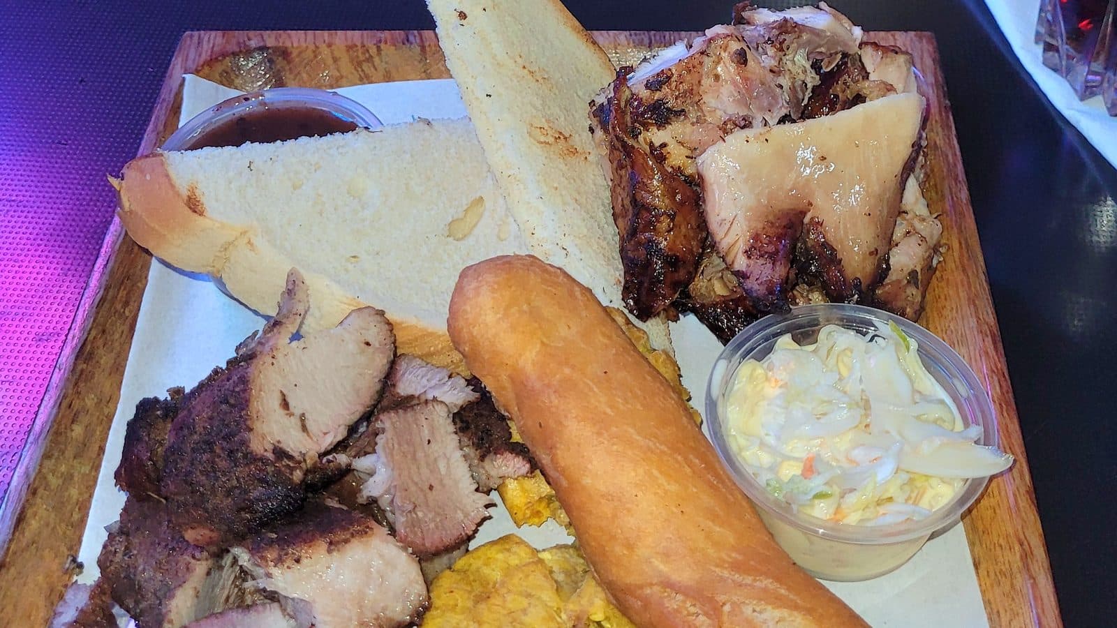 Jerk pork and chicken with festival, plantain, hard-dough bread and sauce in Kingston
